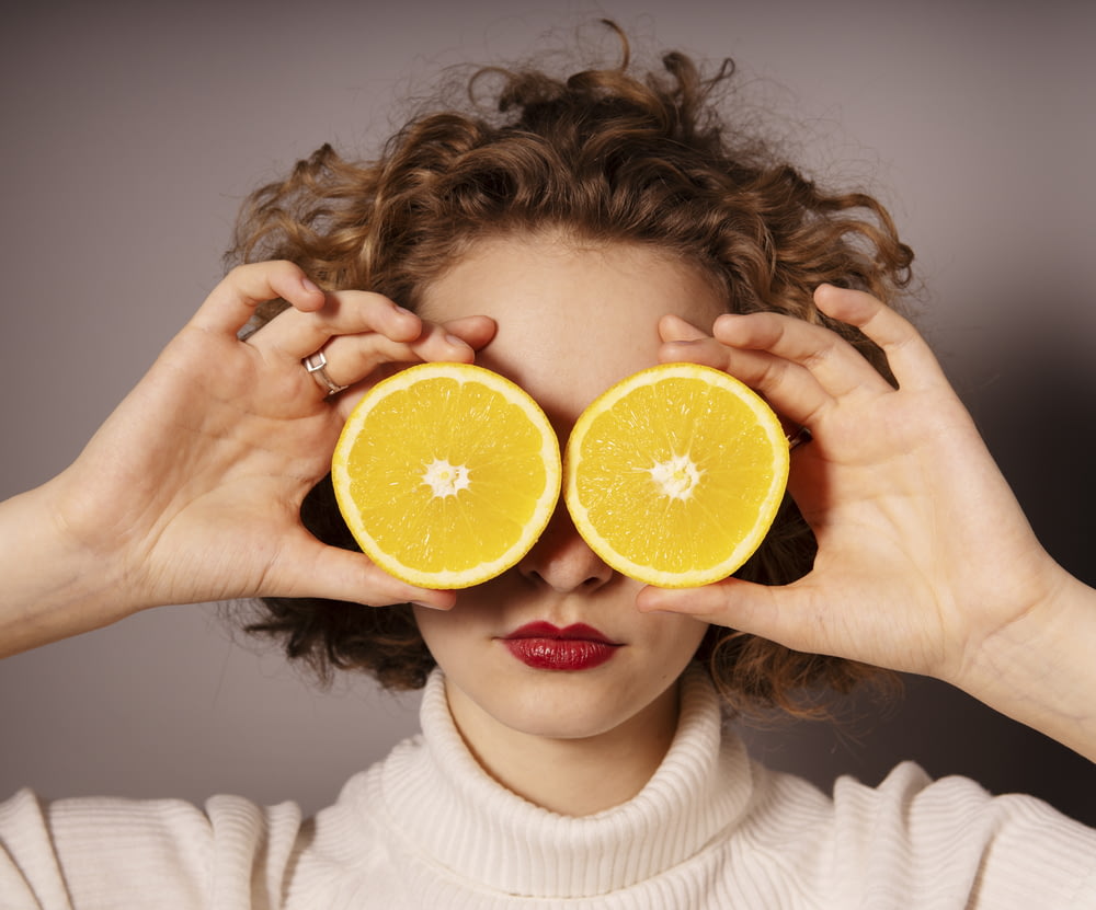 mujer sosteniendo fruta naranja en rodajas
