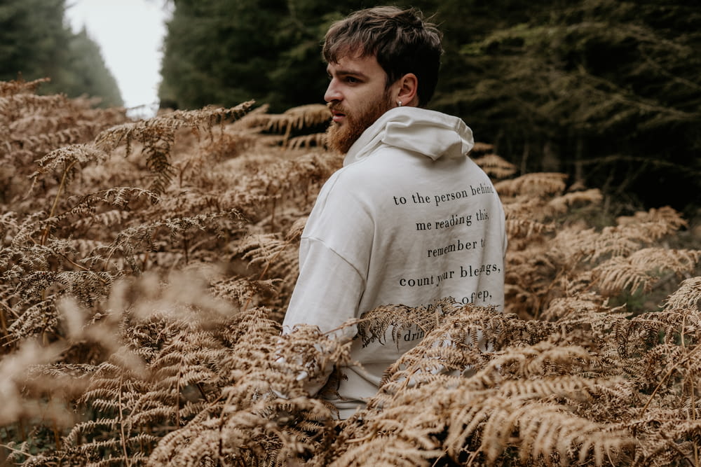 man in white hoodie sitting on brown dried grass during daytime
