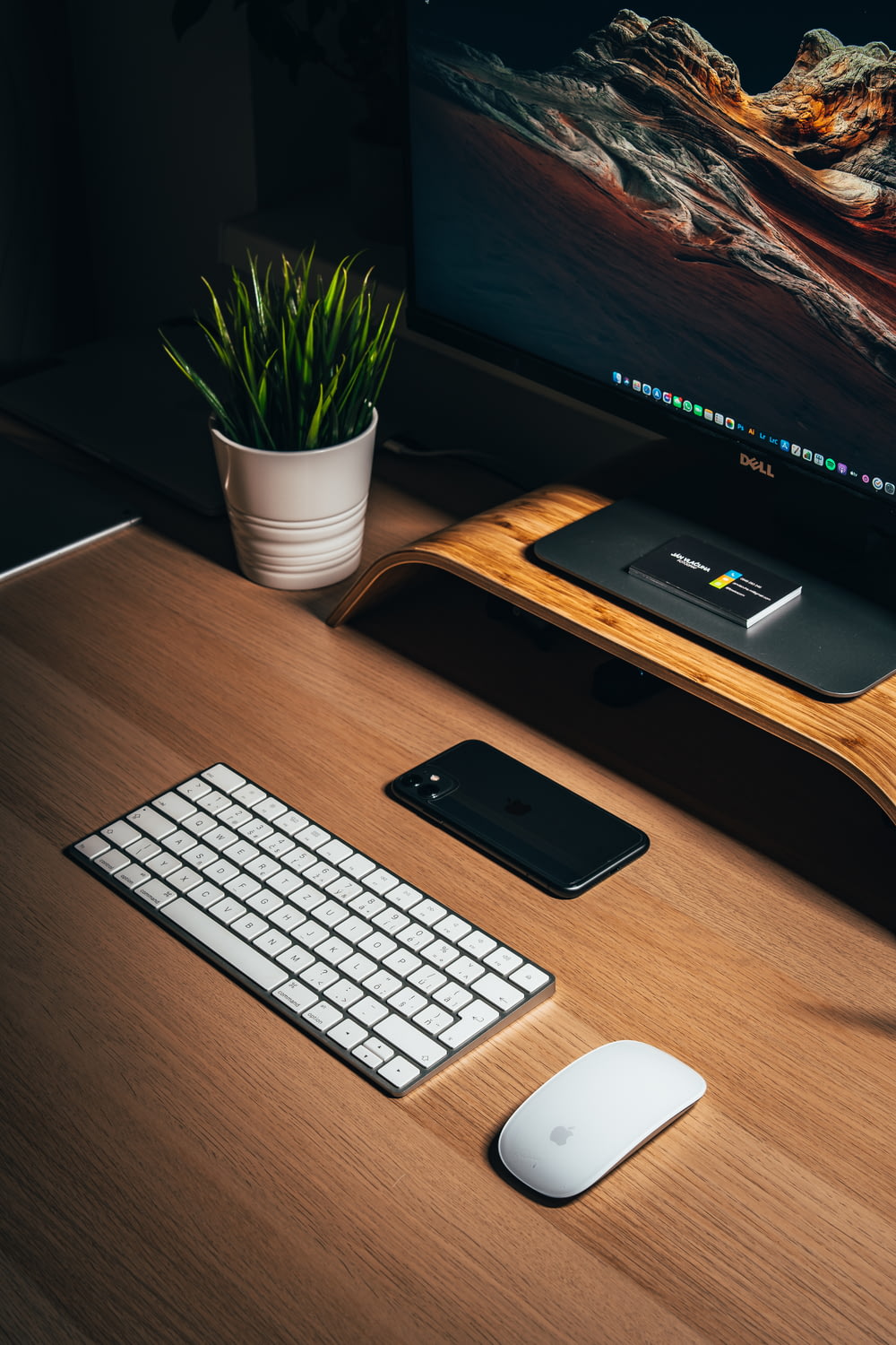 iphone 5 preto ao lado do teclado branco da maçã na mesa de madeira marrom