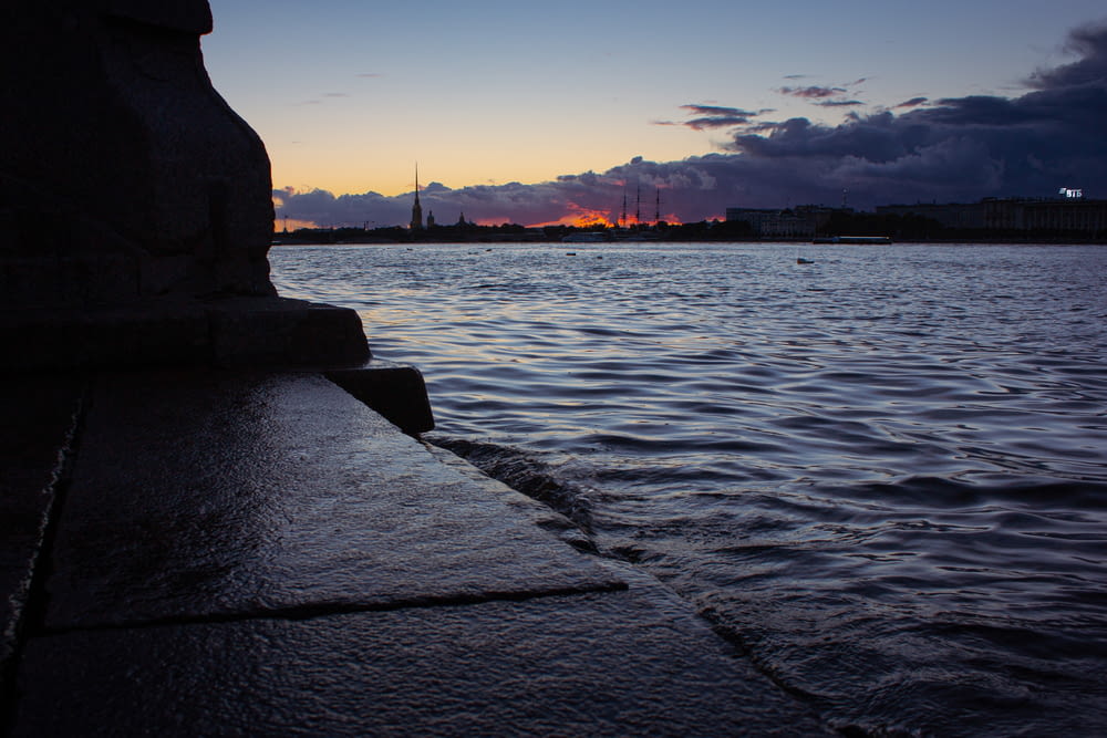 silhouette of statue near body of water during sunset