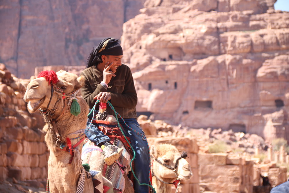man in black helmet riding camel during daytime