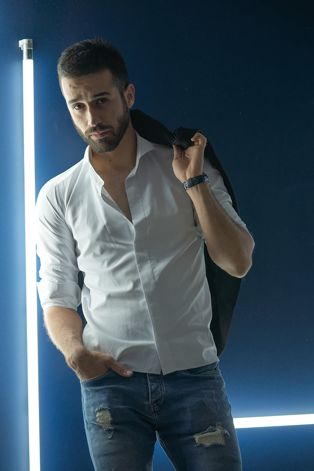 man in white dress shirt and blue denim jeans holding black smartphone