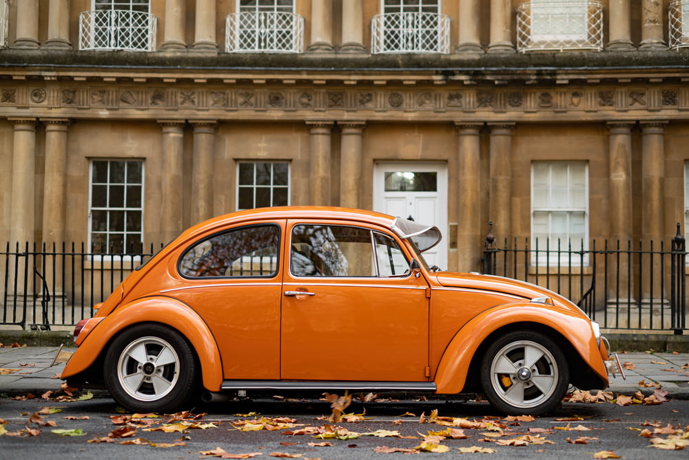 Volkswagen Beetle naranja estacionado cerca del edificio