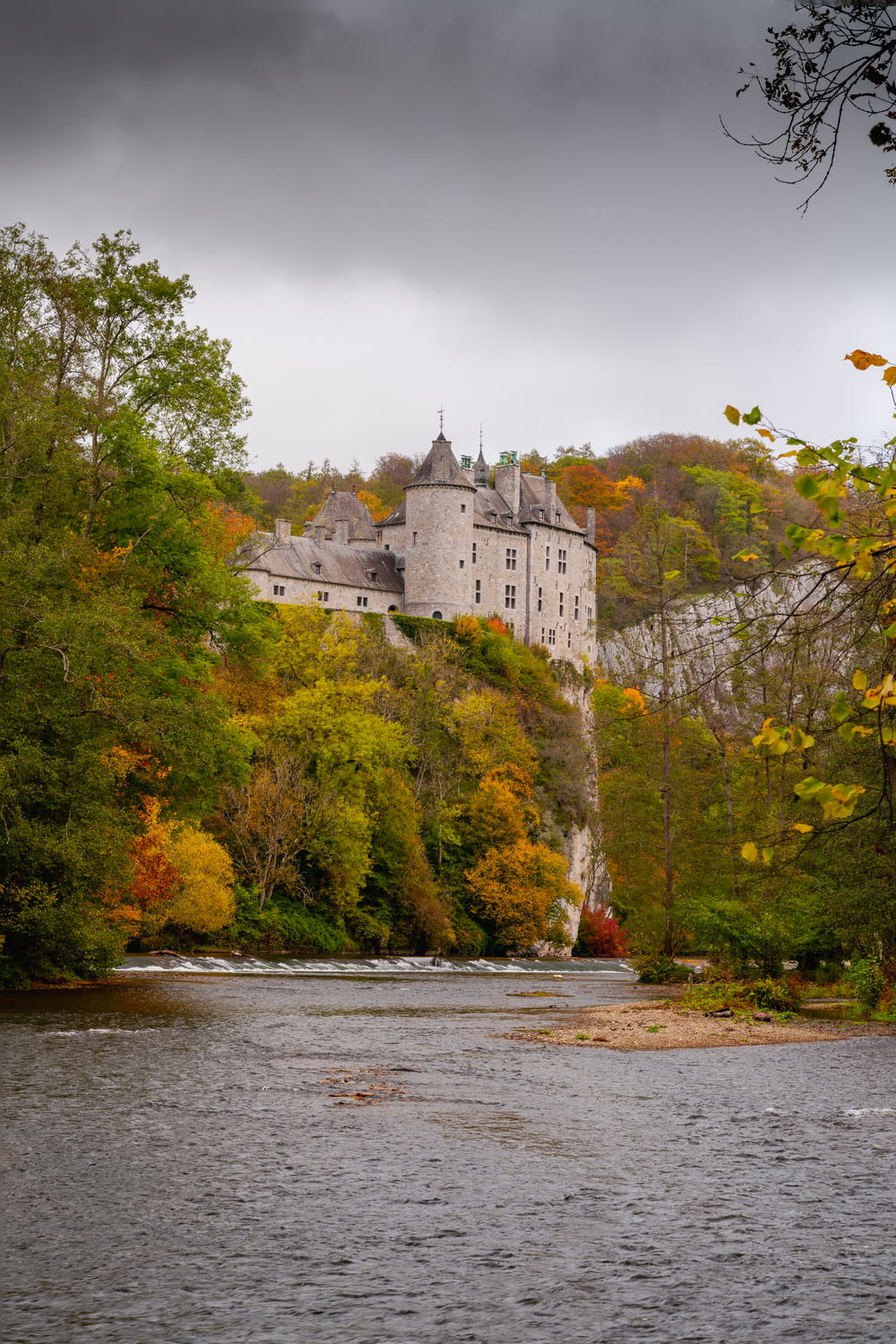 white and gray castle on green trees beside river during daytime