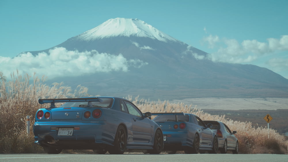 Coupé BMW bleu sur la route près d’une montagne enneigée pendant la journée