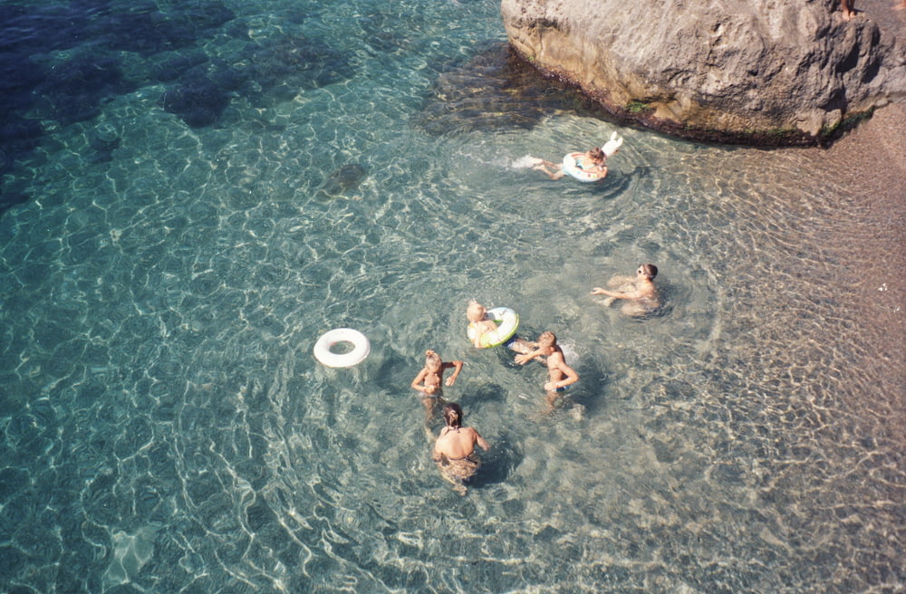 people swimming on body of water during daytime