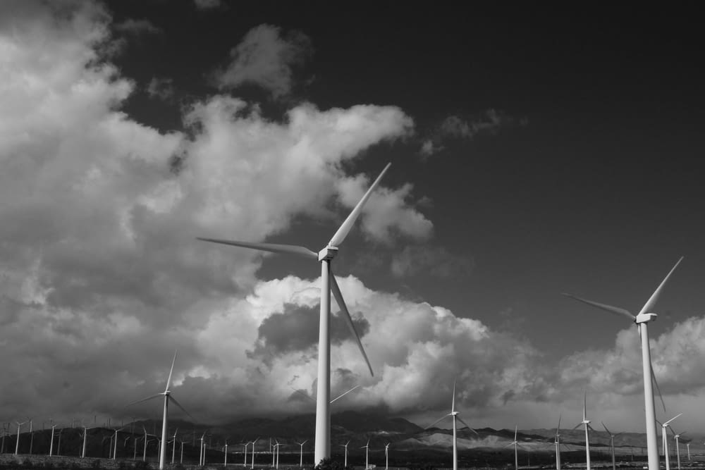 white wind turbine under cloudy sky during daytime