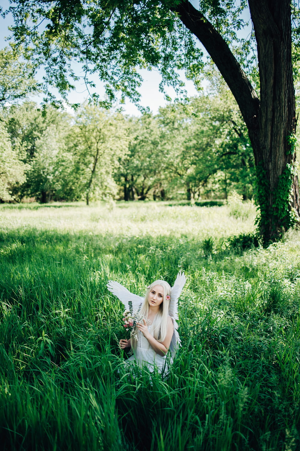 girl in white dress lying on green grass field during daytime