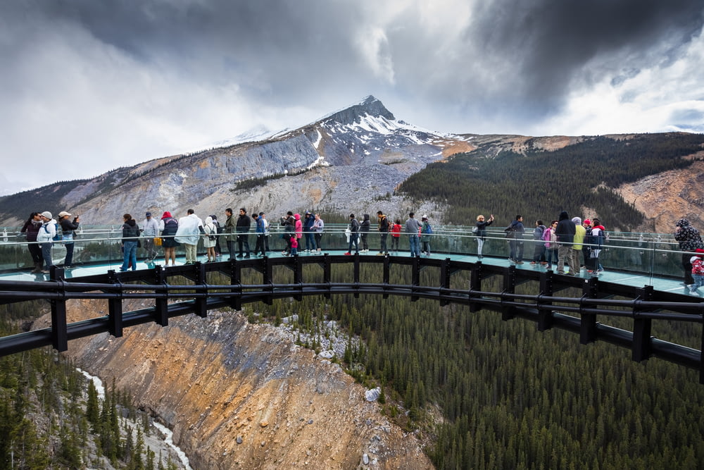 persone in piedi sul ponte vicino alla montagna durante il giorno