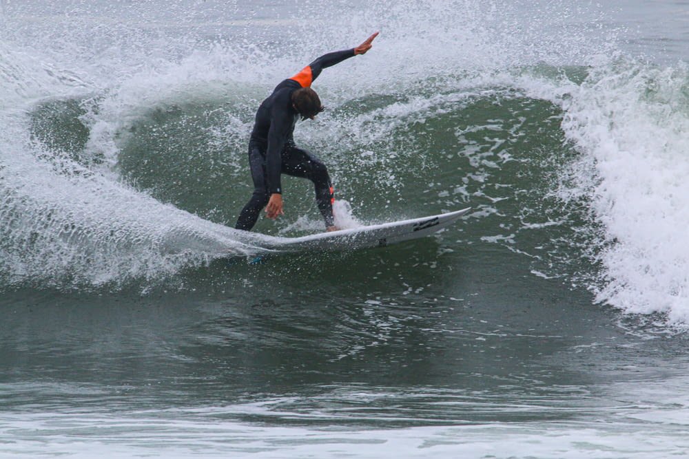 man in black wet suit surfing on water during daytime