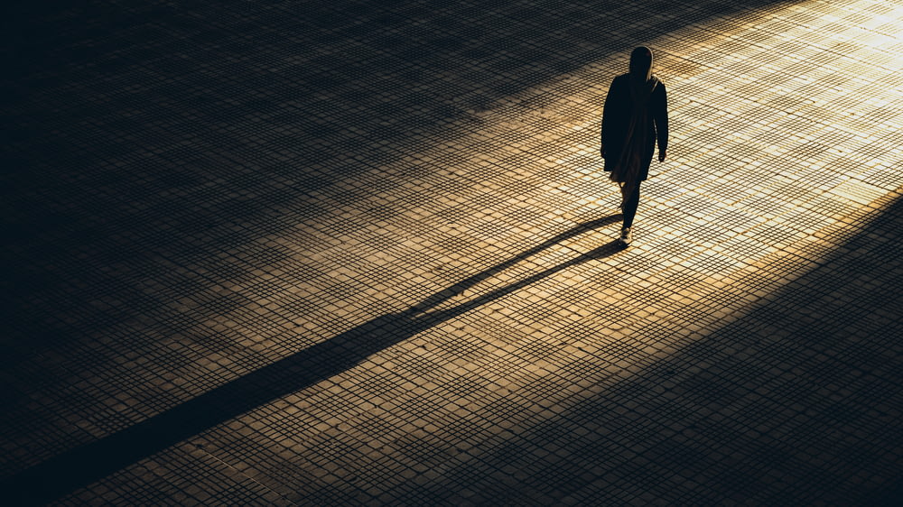 homme en veste noire marchant sur un sol en briques brunes