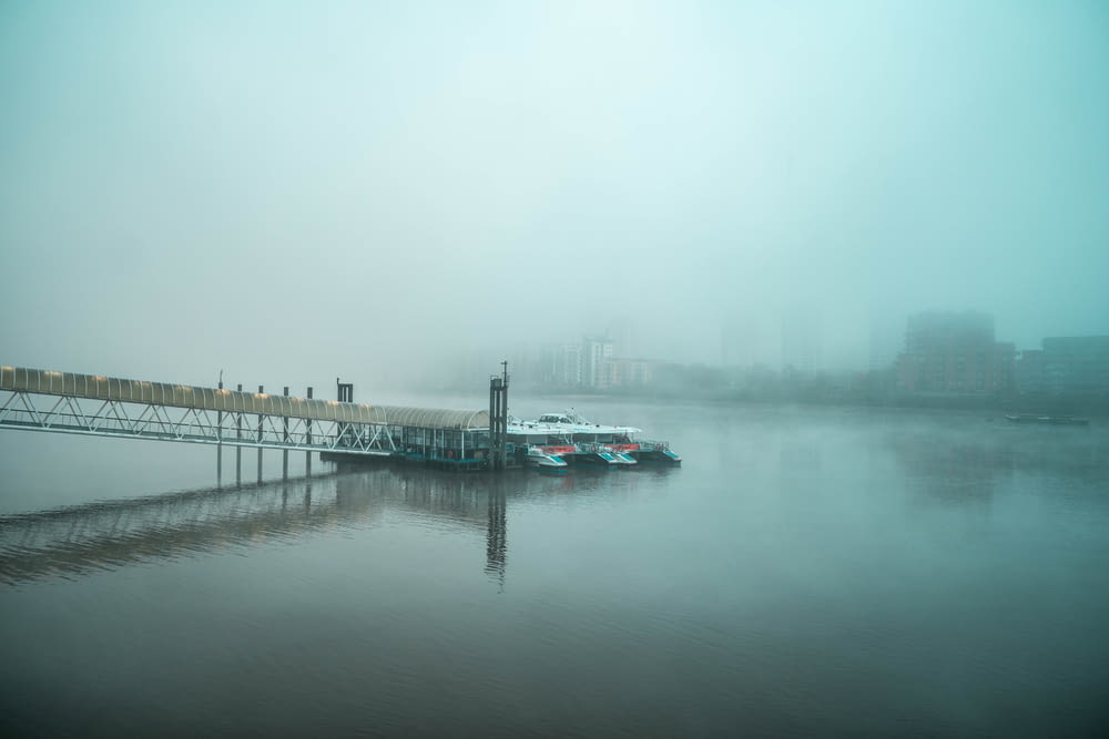 blue and white boat on dock during foggy weather
