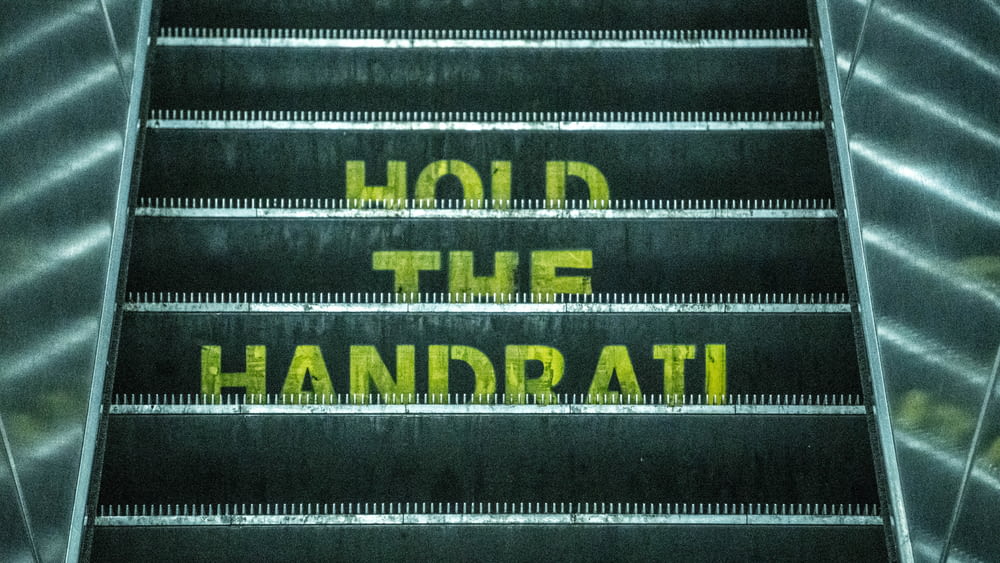 an escalator with the words hold the handrail written on it