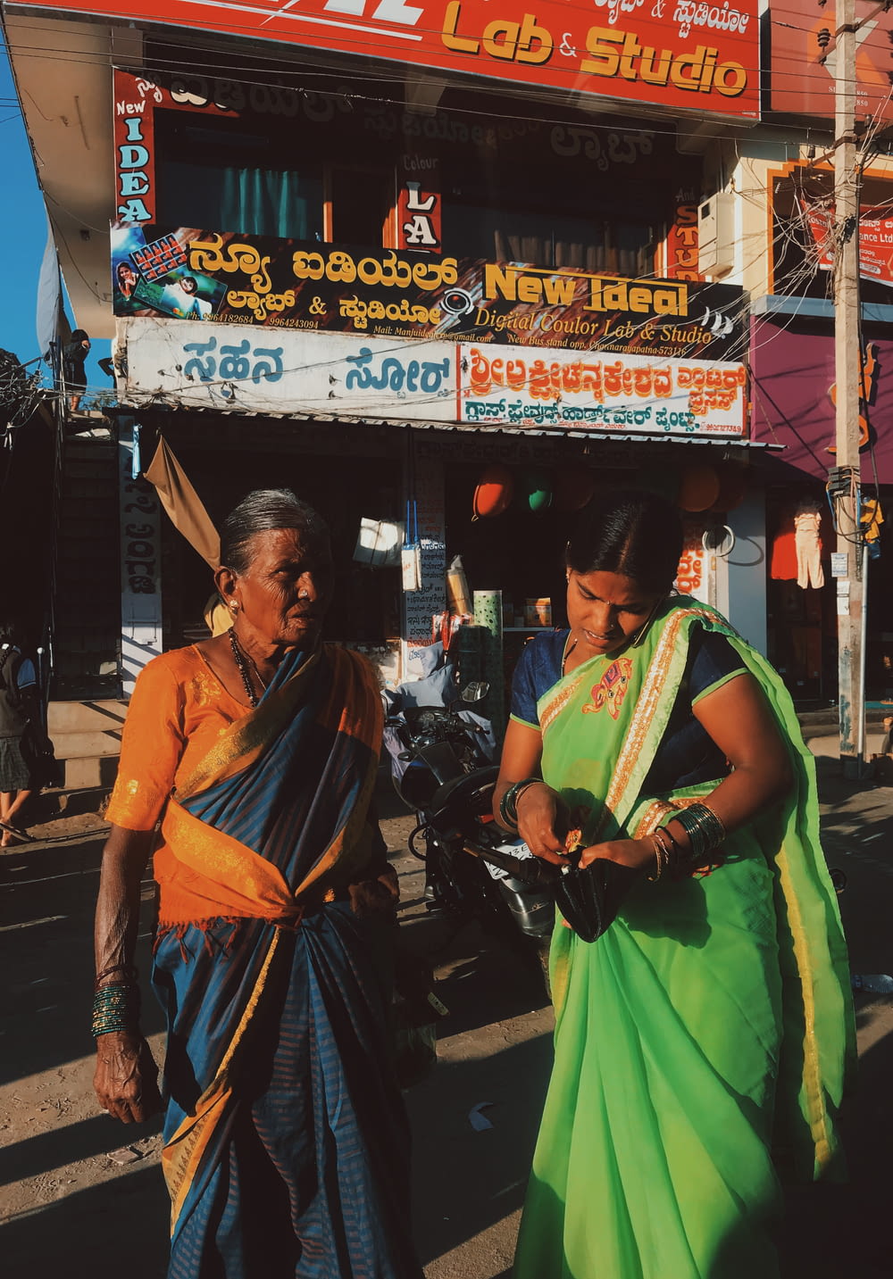 woman in yellow and blue sari standing on sidewalk during daytime