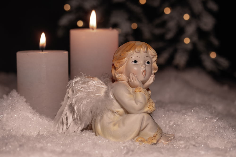 angel ceramic figurine beside white pillar candle
