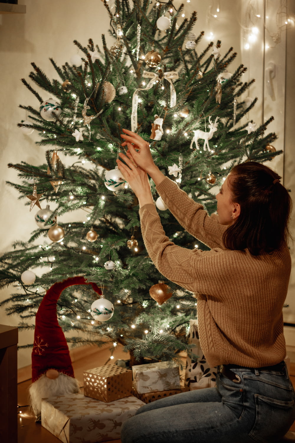 woman in brown sweater holding green christmas tree