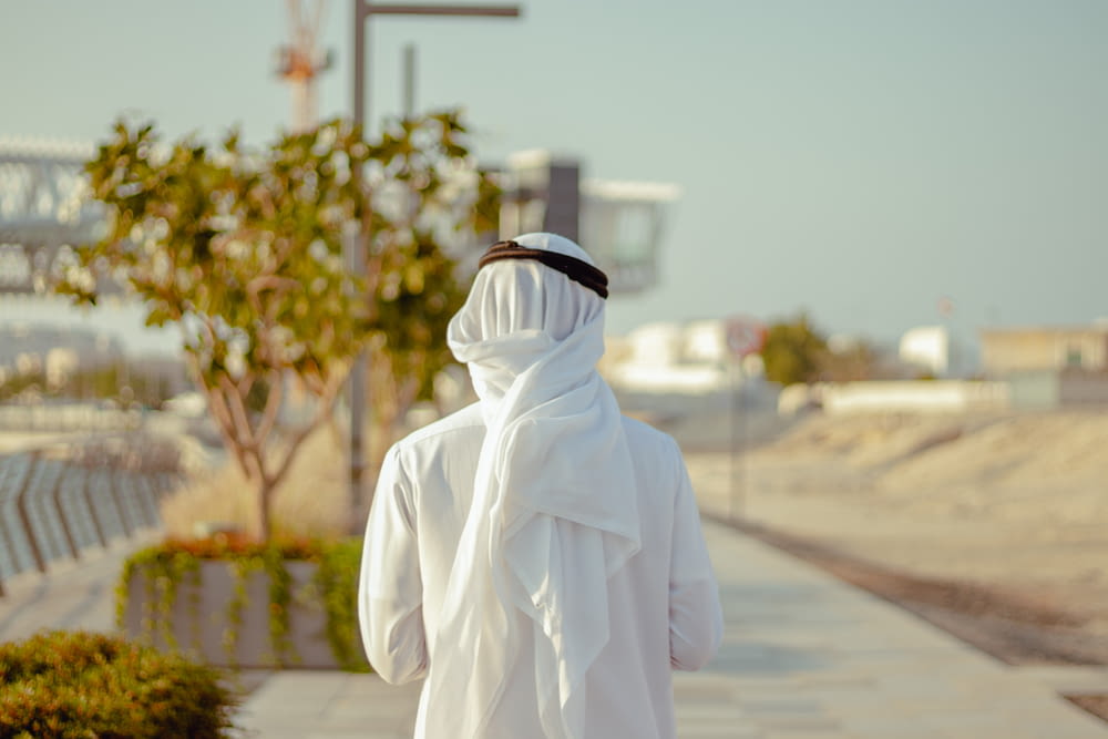 Persona con túnica blanca de pie en la carretera durante el día