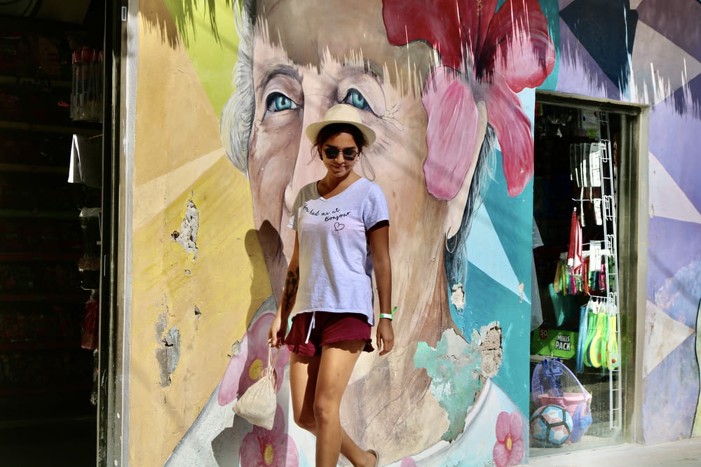 woman in white shirt and black shorts standing beside wall with graffiti