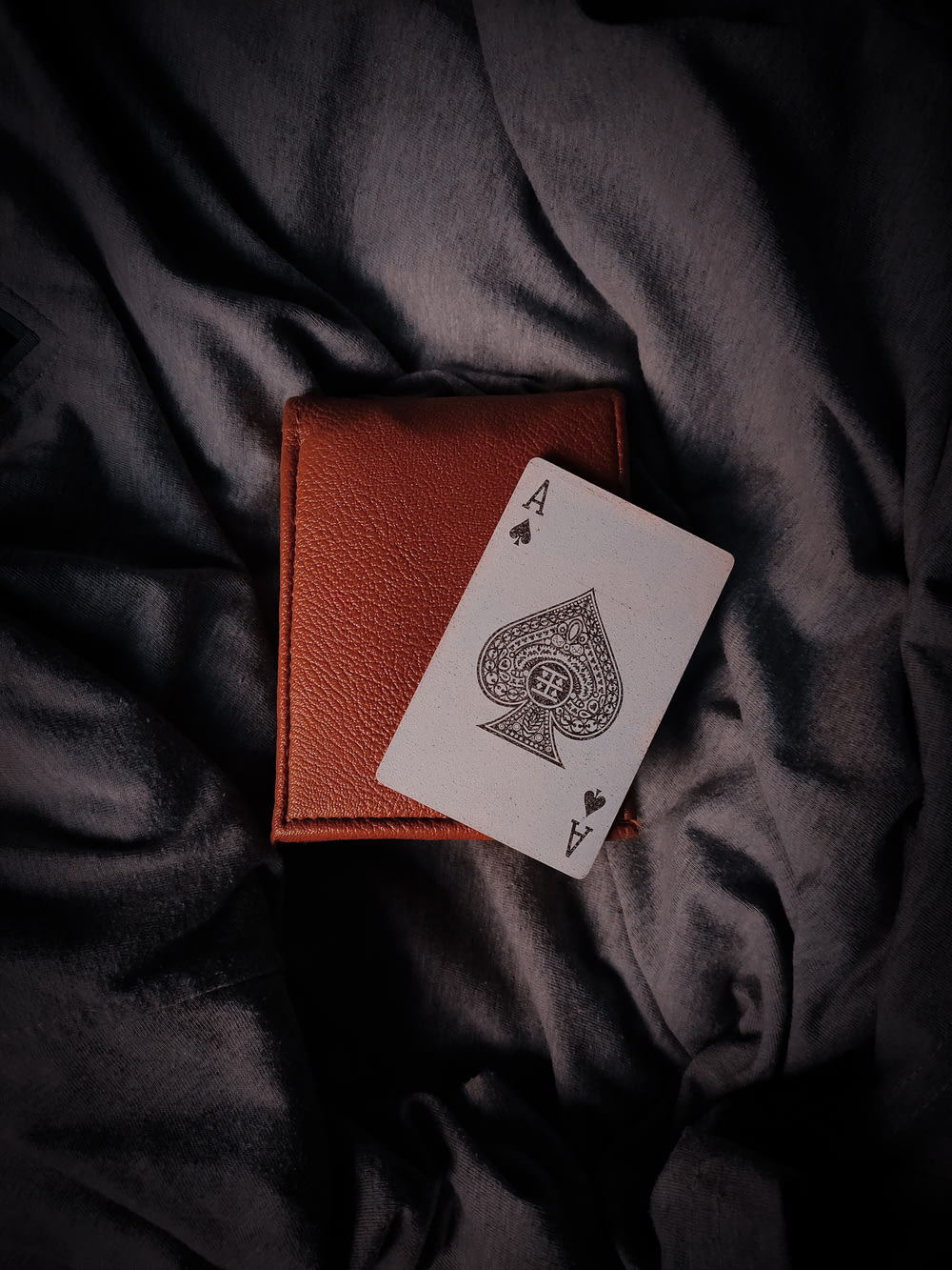 ace of spade playing card on brown leather wallet