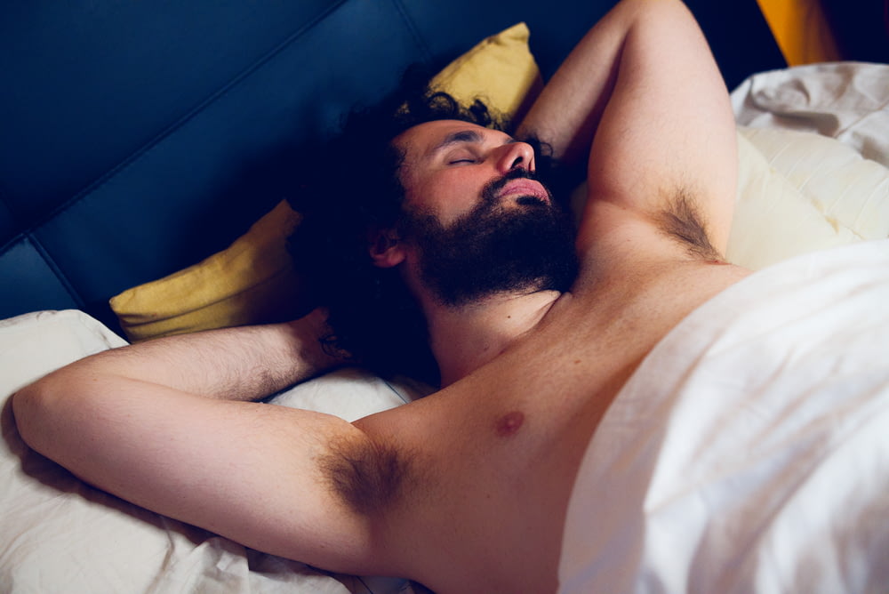 topless man lying on bed