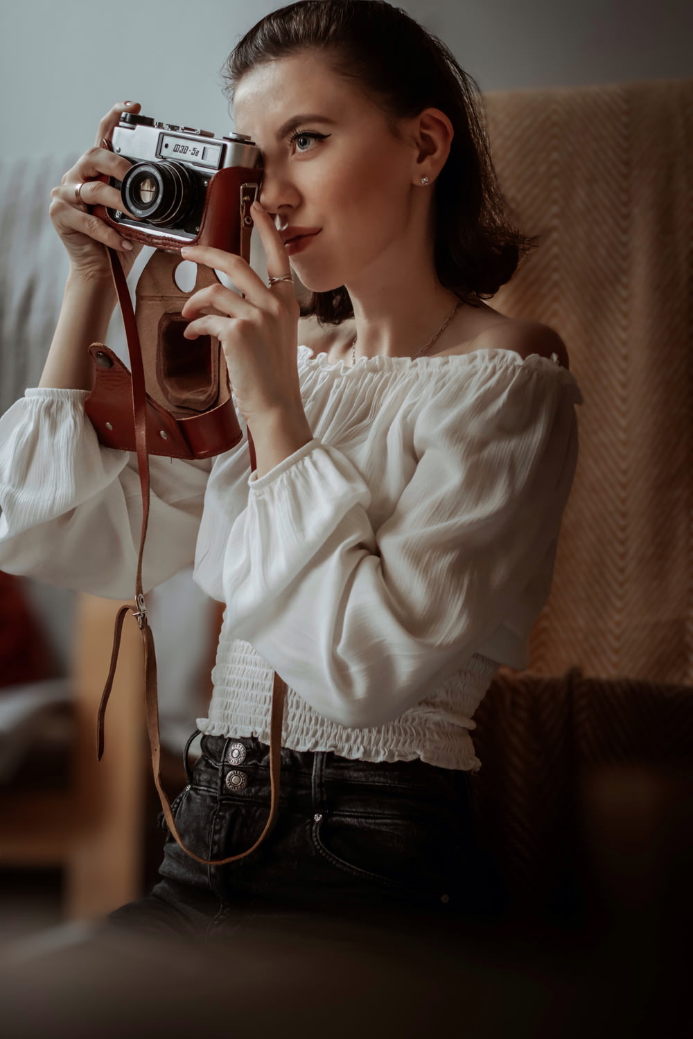 woman in white long sleeve shirt holding black camera