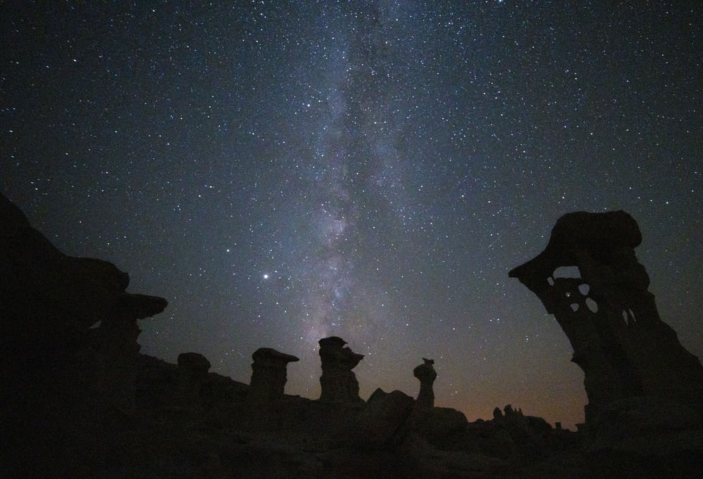 silhouette of people on rock formation under starry night