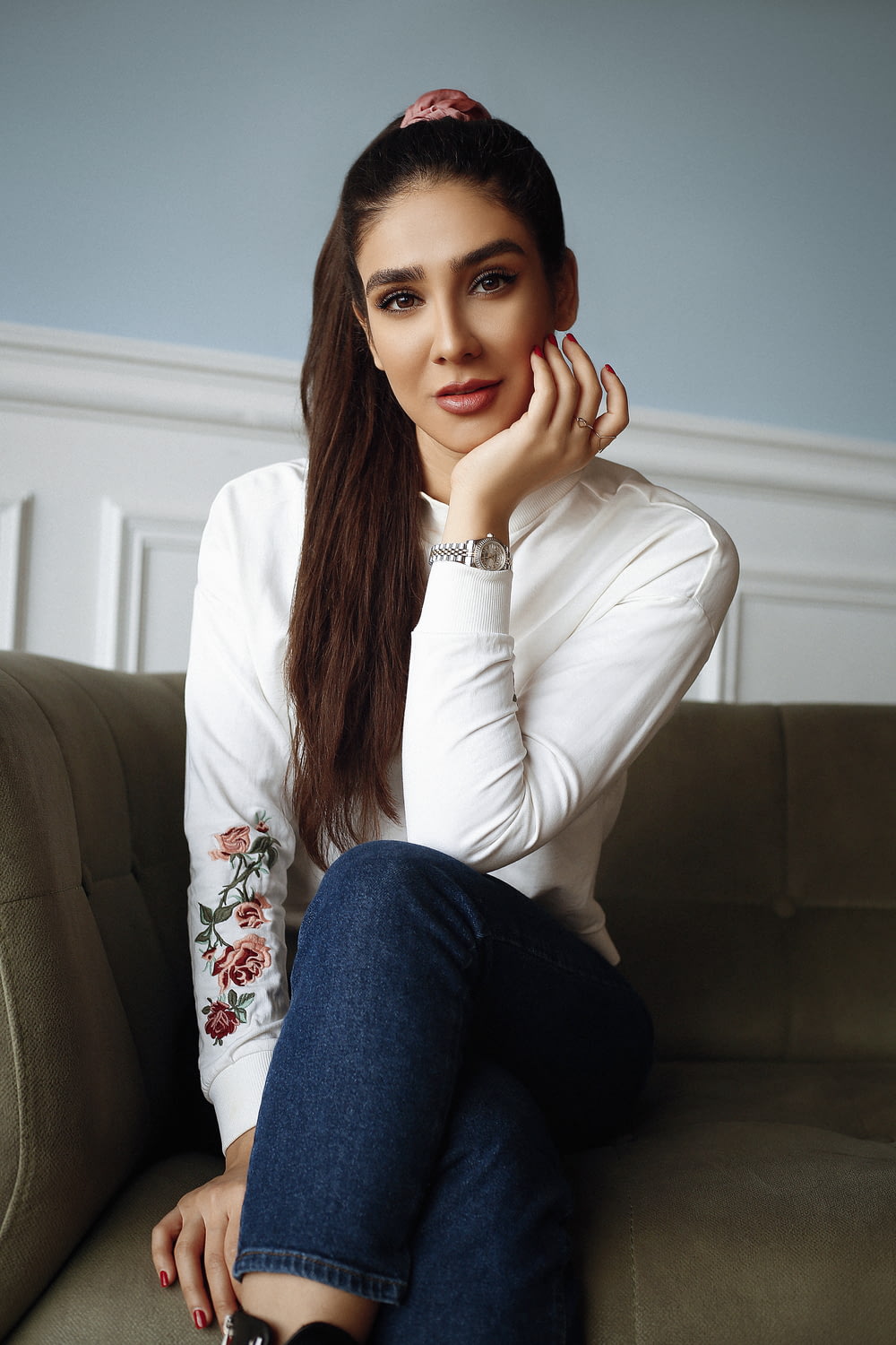 woman in white long sleeve shirt and blue denim jeans sitting on gray couch