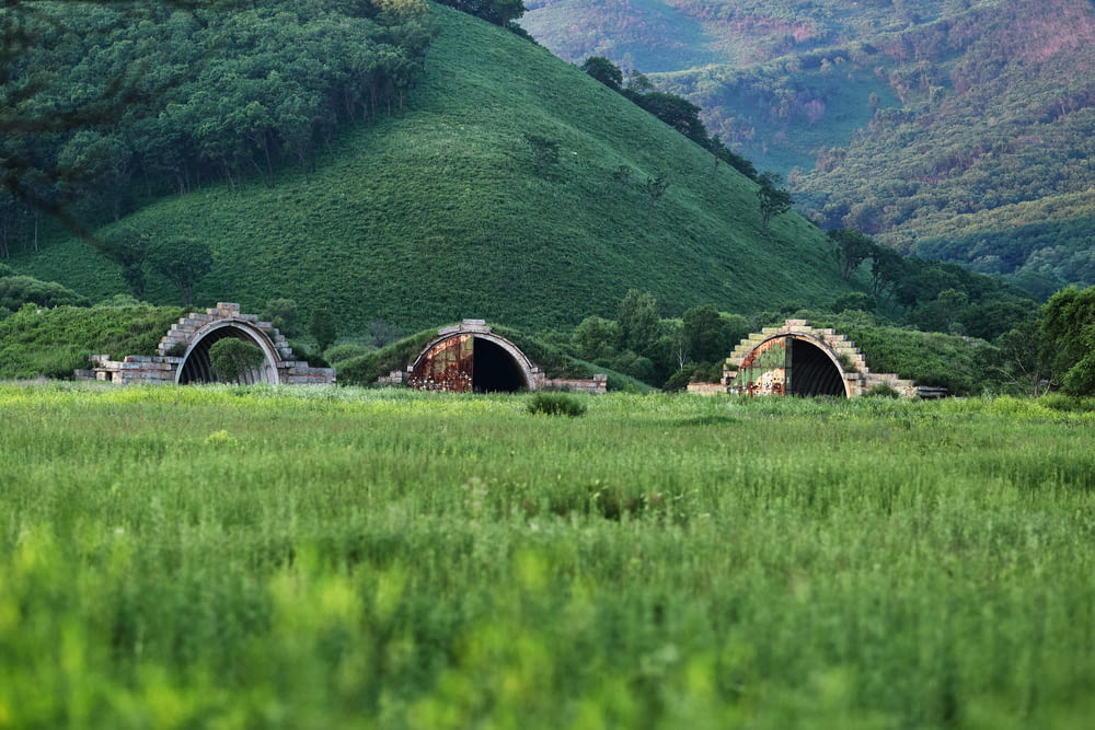 Puente de madera marrón en un campo de hierba verde cerca de las montañas verdes durante el día