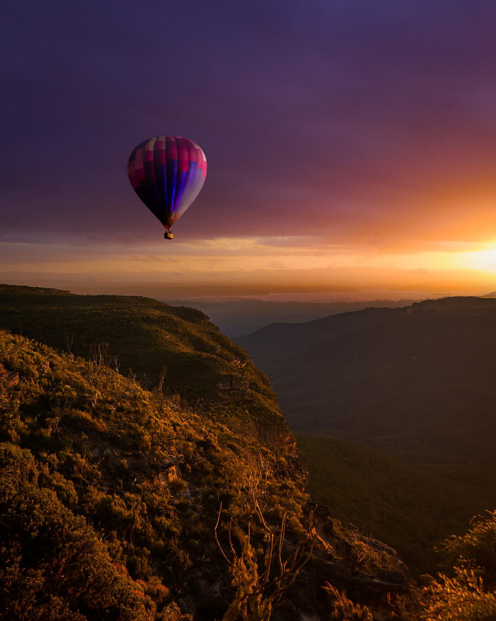 hot air balloon flying over the mountains during sunset