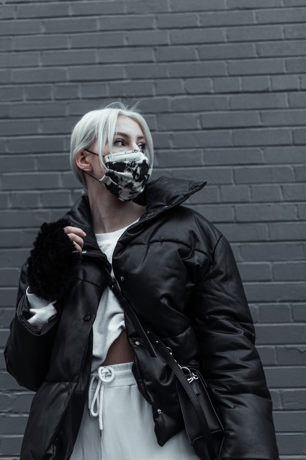 woman in black leather jacket wearing white face mask