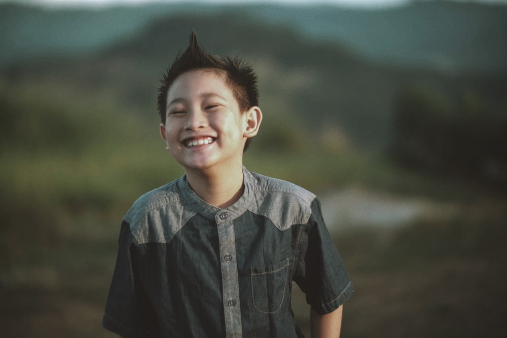 a young boy with a mohawk smiles at the camera
