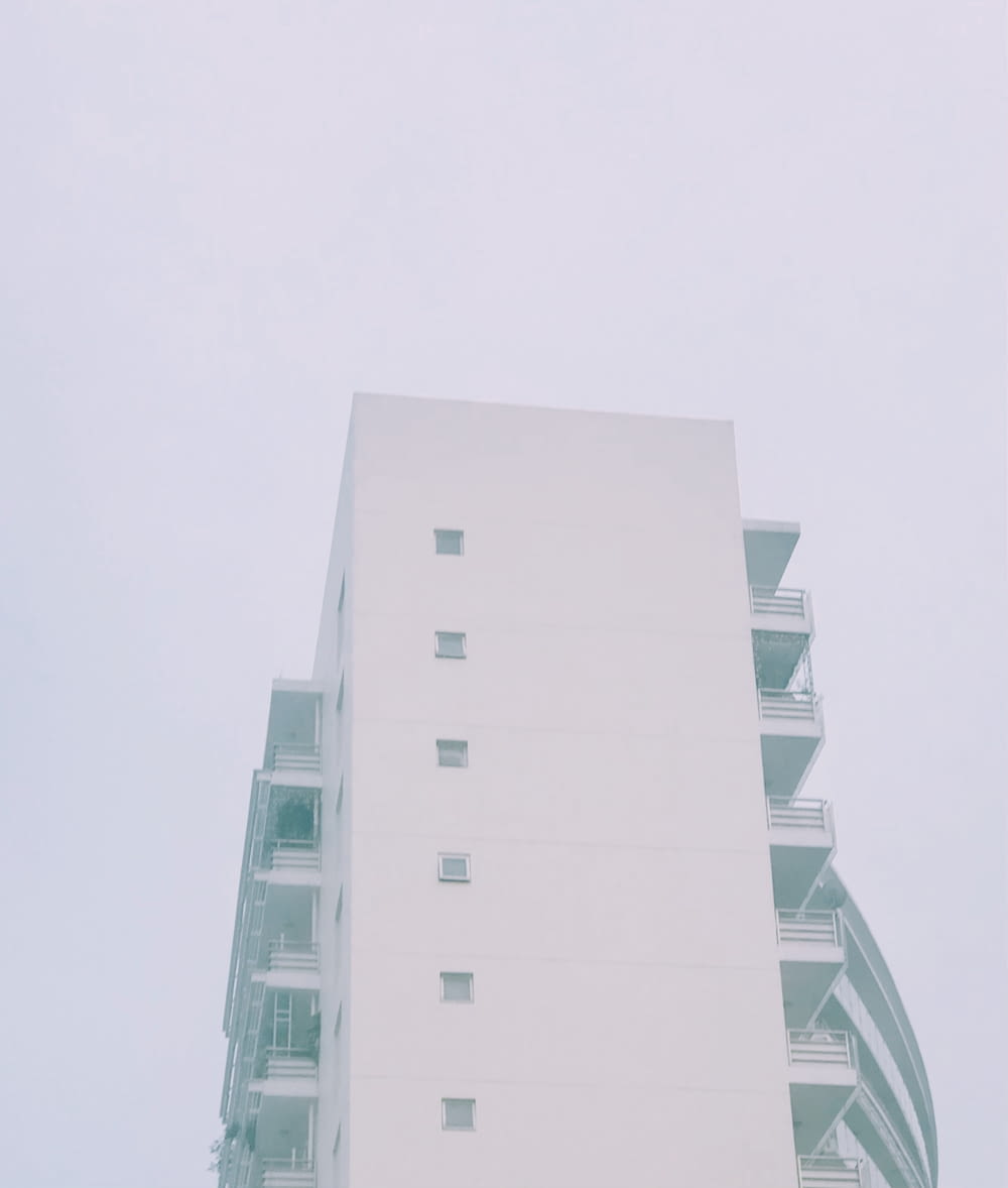 a tall white building sitting next to a parking meter