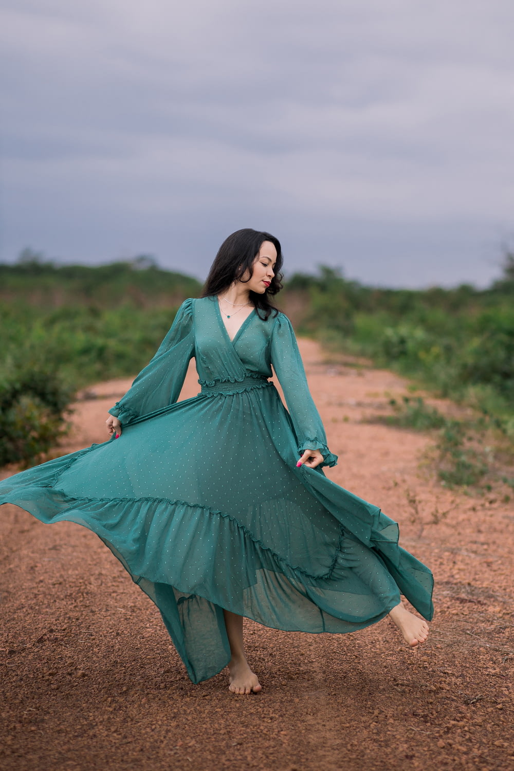 femme en robe verte à manches longues debout sur le champ brun pendant la journée