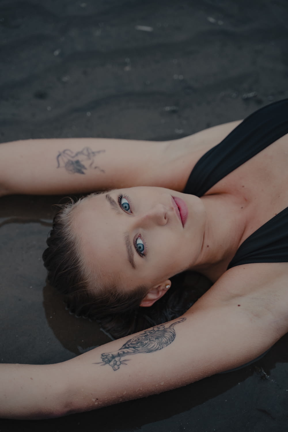 woman in black tank top lying on the beach