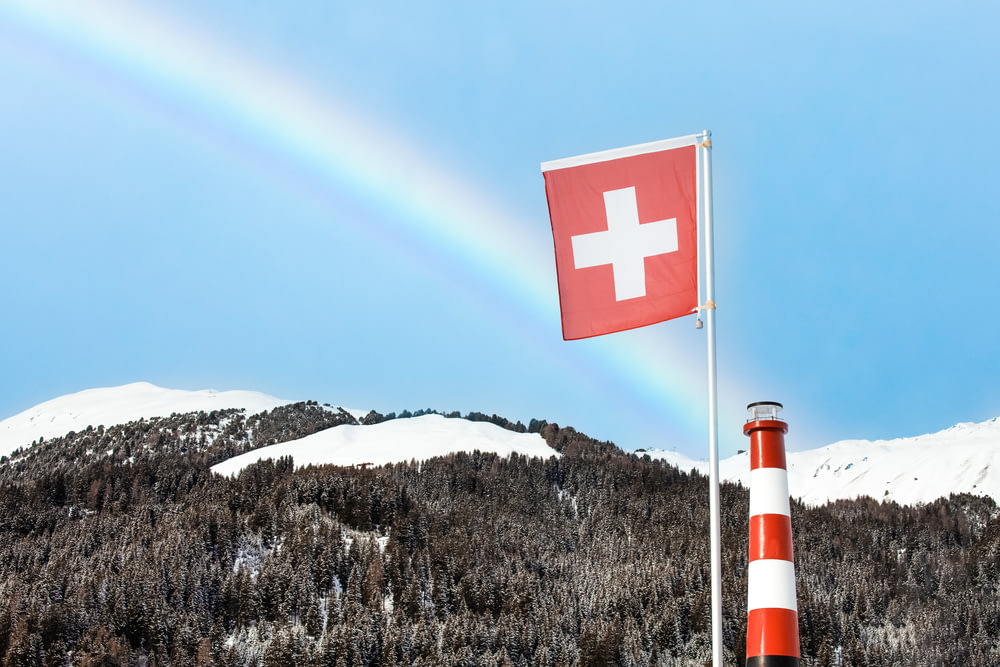 Bandera roja y blanca de la cruz en la cima de la montaña