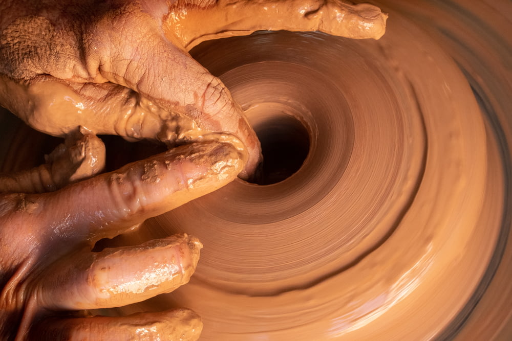 person making clay pot during daytime