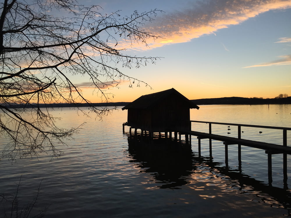 brown wooden house on body of water during sunset