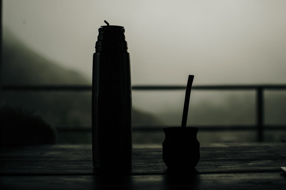 schwarze Flasche mit weißem Stroh auf braunem Holztisch
