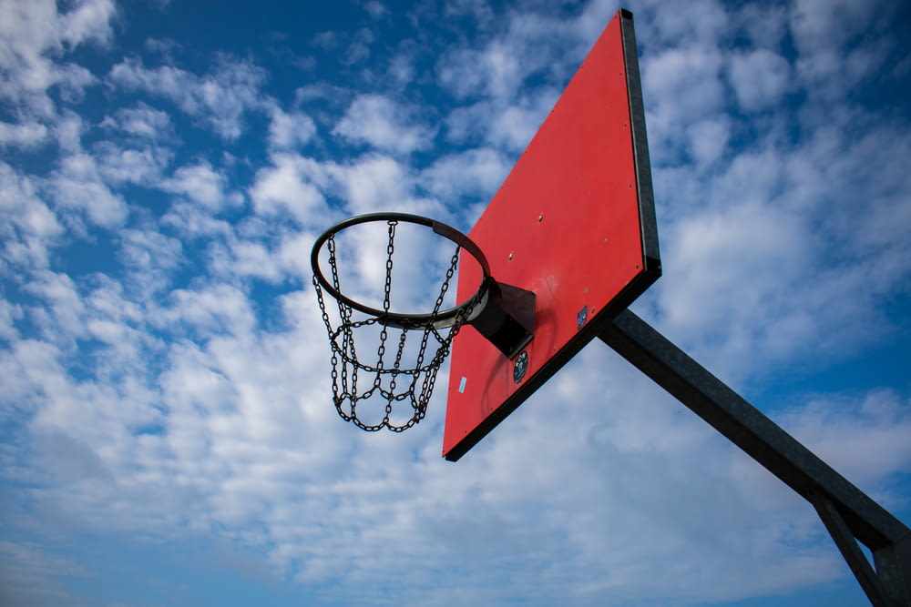 red and black basketball hoop under blue sky