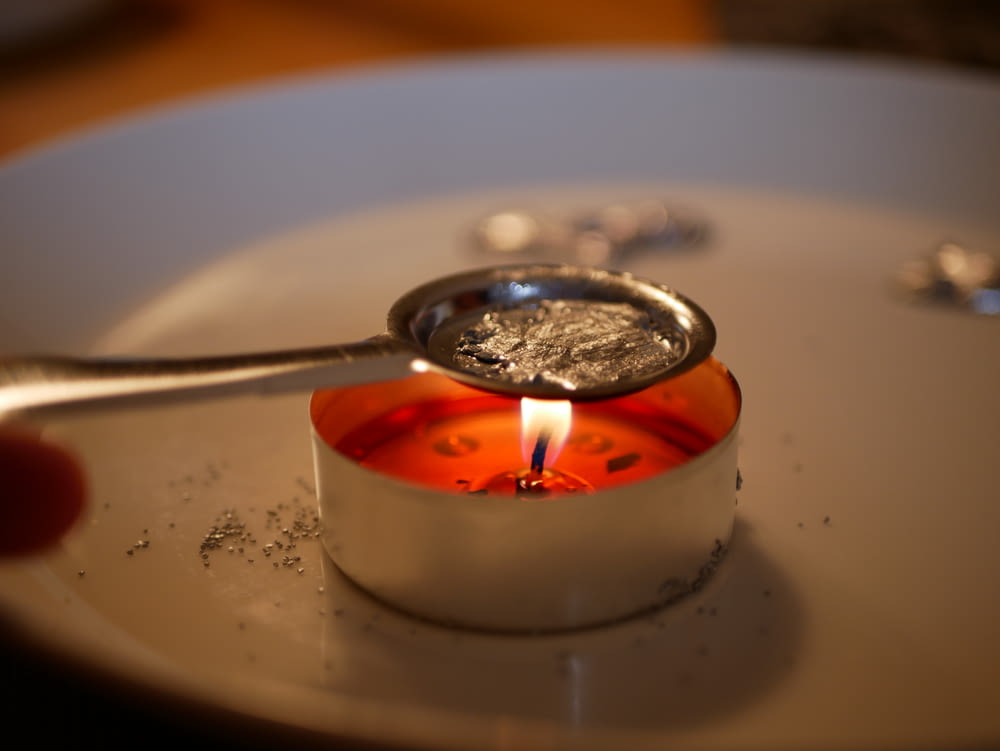 흰색 세라믹 접시에 불을 붙인 촛불