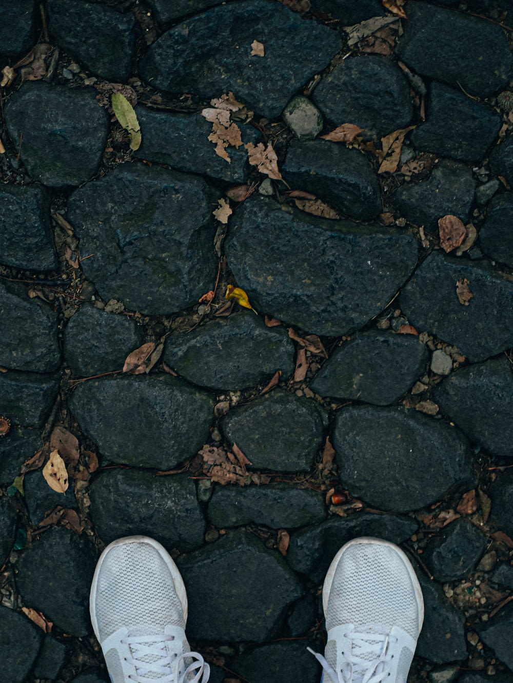 pessoa vestindo tênis branco e cinza em pé no chão de concreto cinza