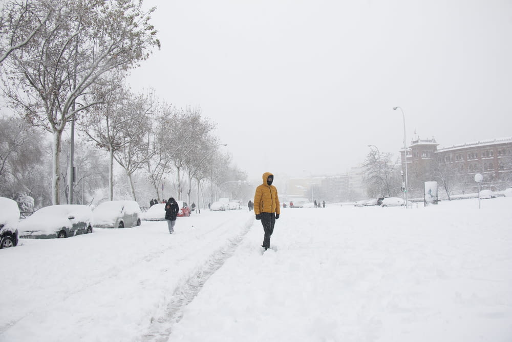 person in yellow jacket walking on snow covered ground during daytime