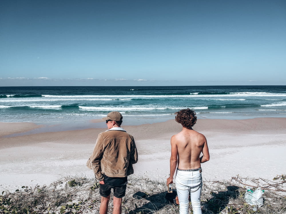 2 hommes debout sur la plage pendant la journée