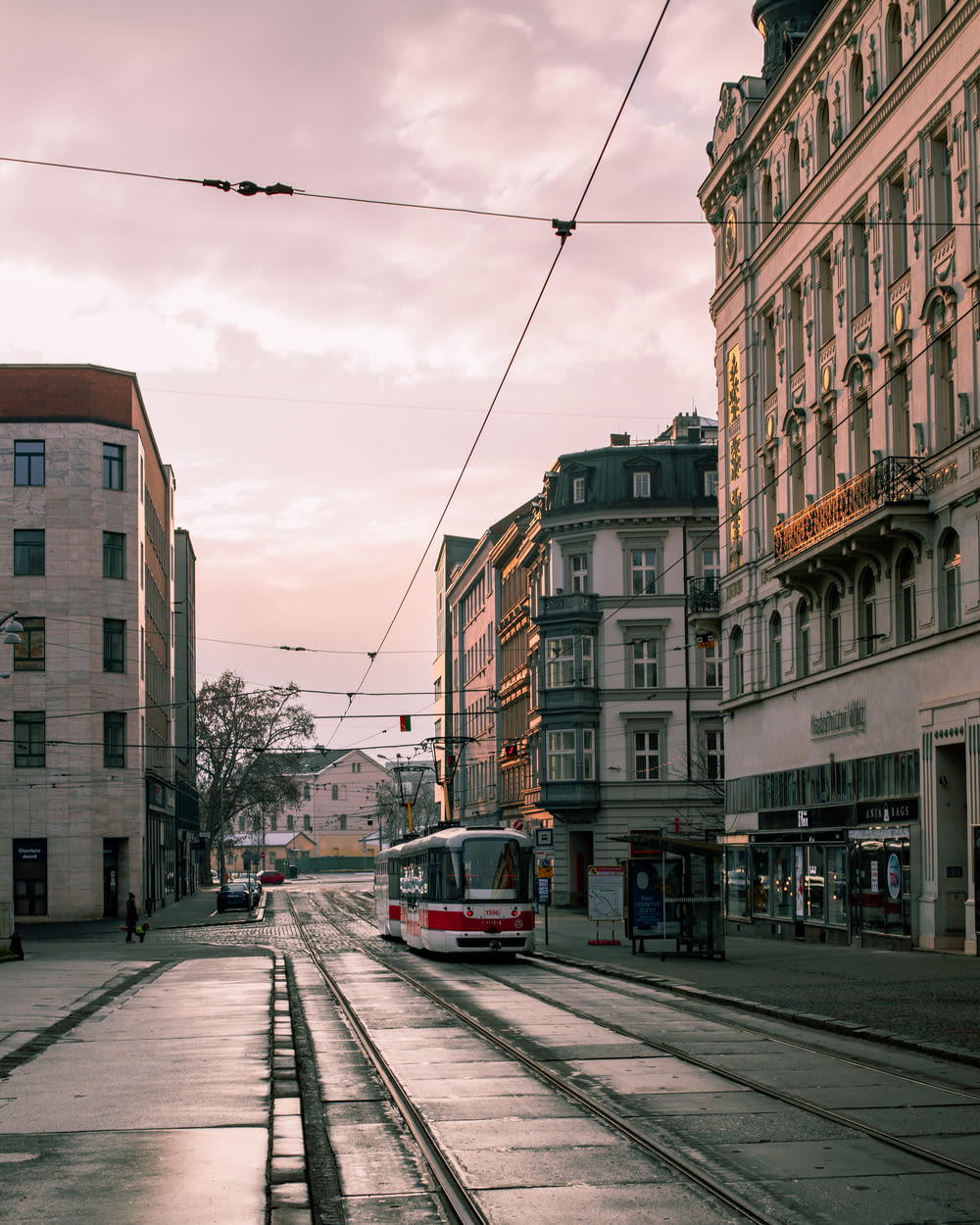 tram rosso e bianco sulla strada vicino all'edificio in cemento marrone durante il giorno