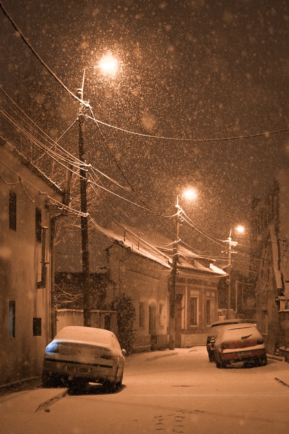 dois carros estacionados em uma rua nevada à noite