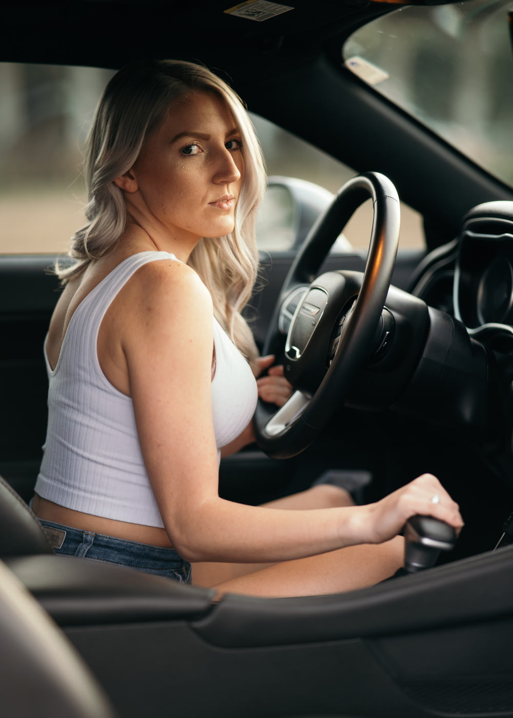 woman in white tank top driving car