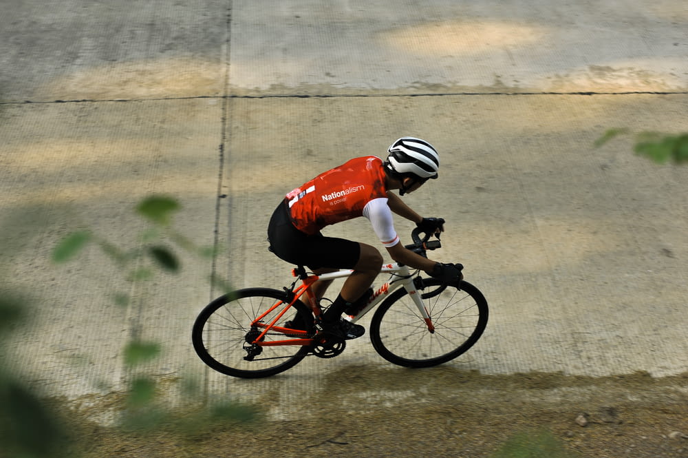 man in red and white bicycle helmet riding on black and white bicycle during daytime