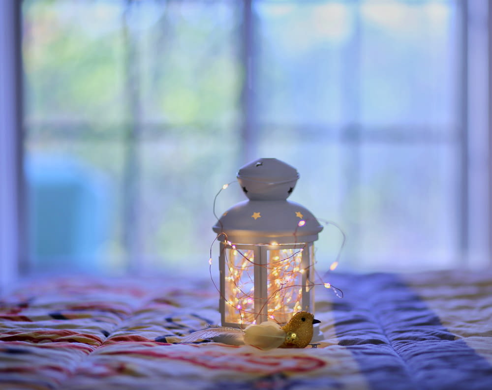 yellow candle lantern on purple and white textile