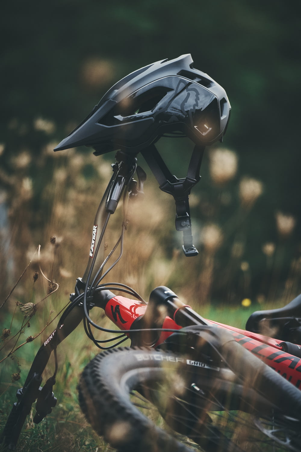 black and red bicycle helmet on brown grass during daytime
