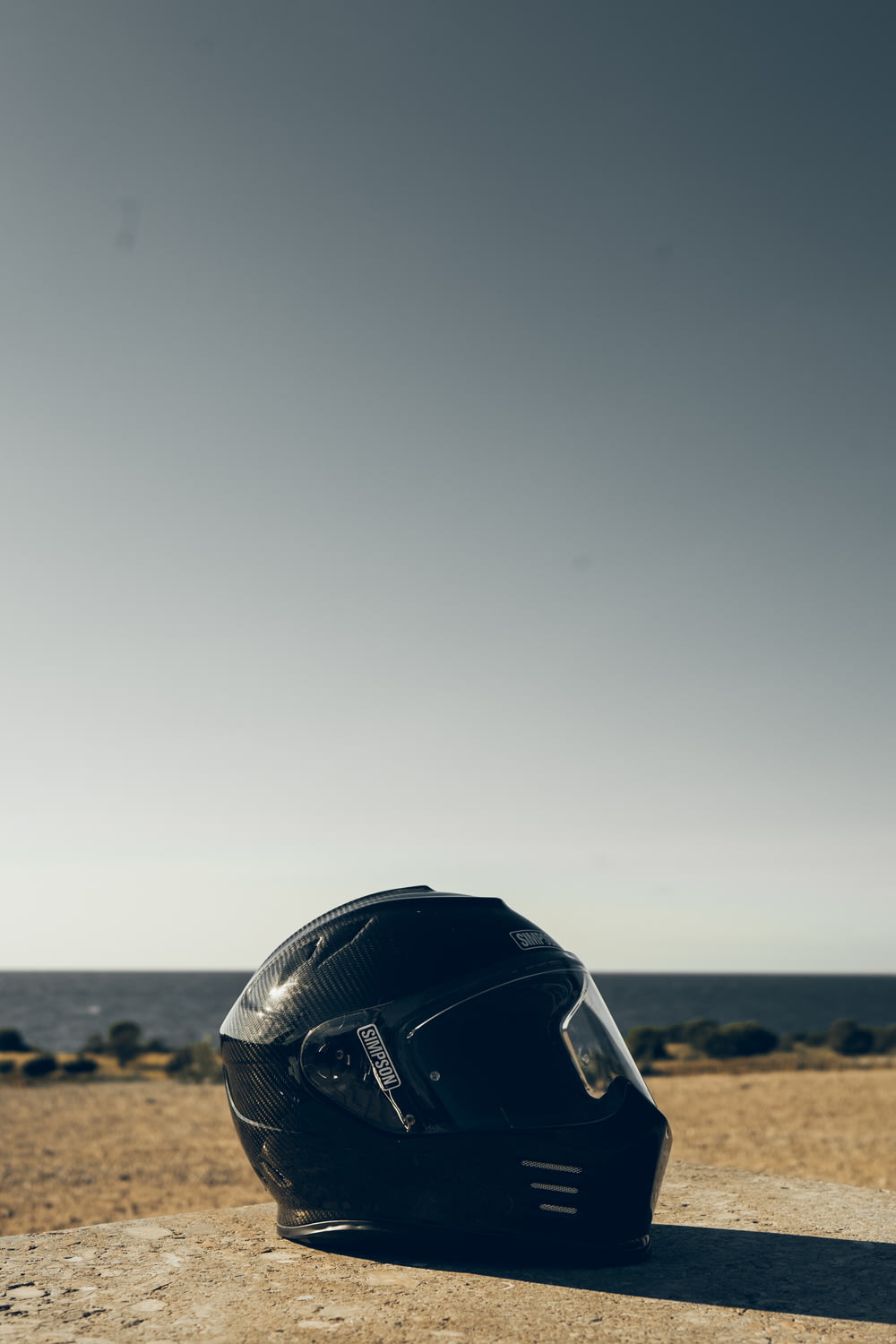 schwarzer Motorradhelm tagsüber auf braunem Sand